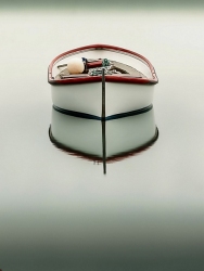 A small white boat with red trim floats on perfectly still water, its reflection forming a serene, symmetrical scene. (Colour image)