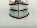 A small white boat with red trim floats on perfectly still water, its reflection forming a serene, symmetrical scene. (Colour image)