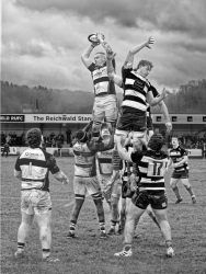 Black‑and‑white sports photograph capturing a rugby line‑out with players lifted to contest the ball.